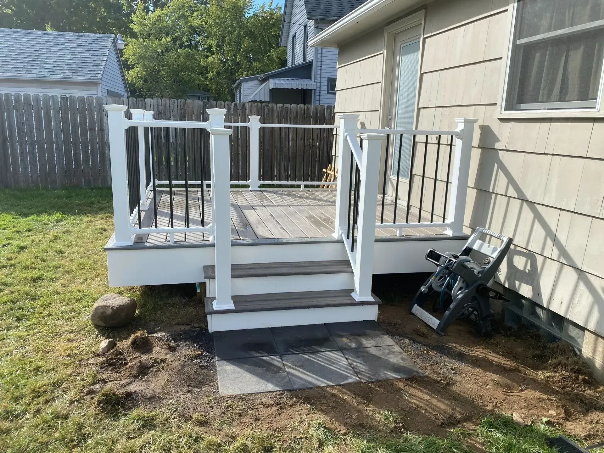 A deck with stairs and a railing is in the backyard of a house.