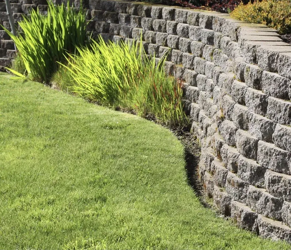 A stone wall surrounds a lush green lawn.