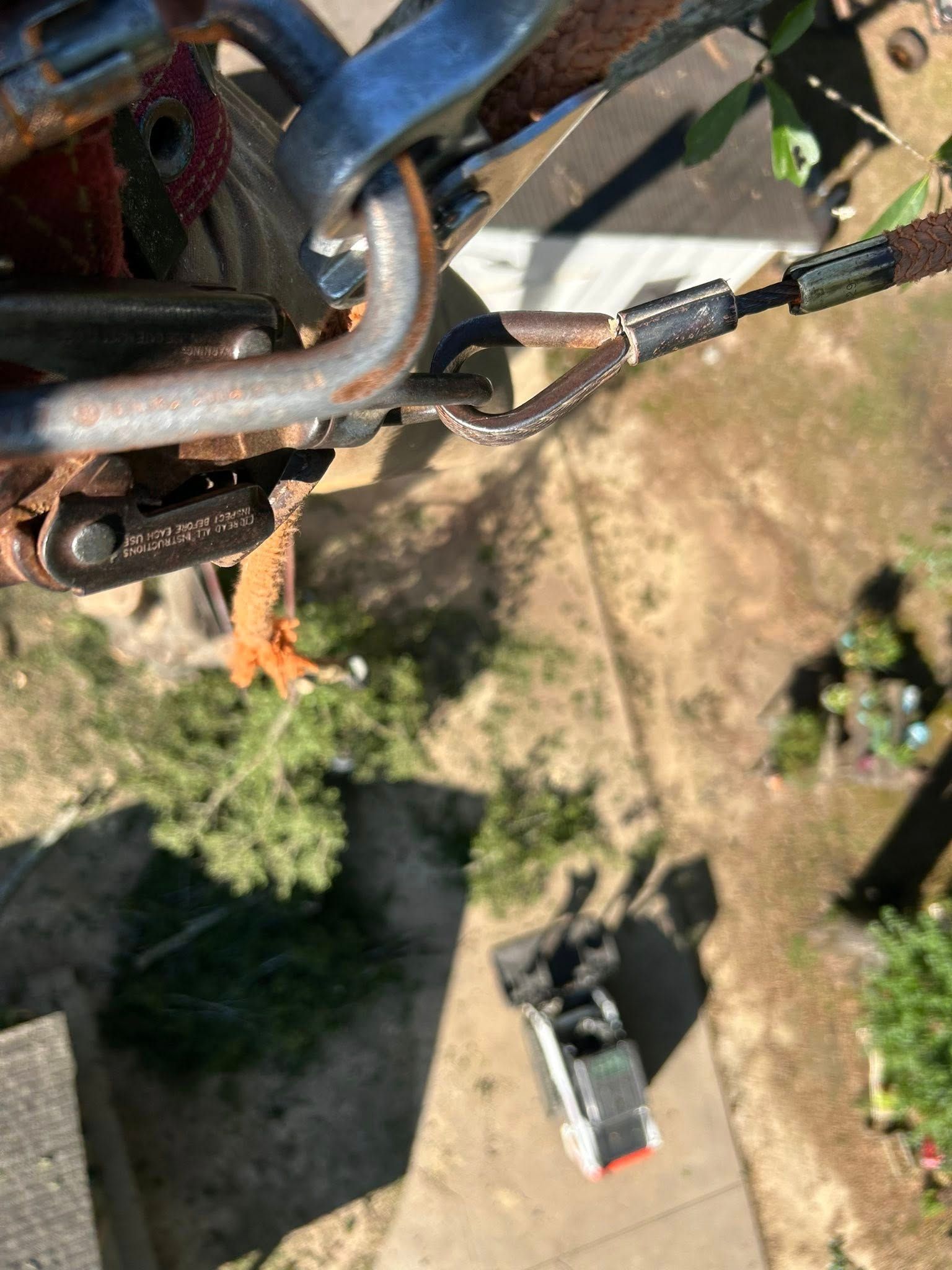 Close-up of a cable lock clipped to blue metal bars, with a yard and parked trailer below.