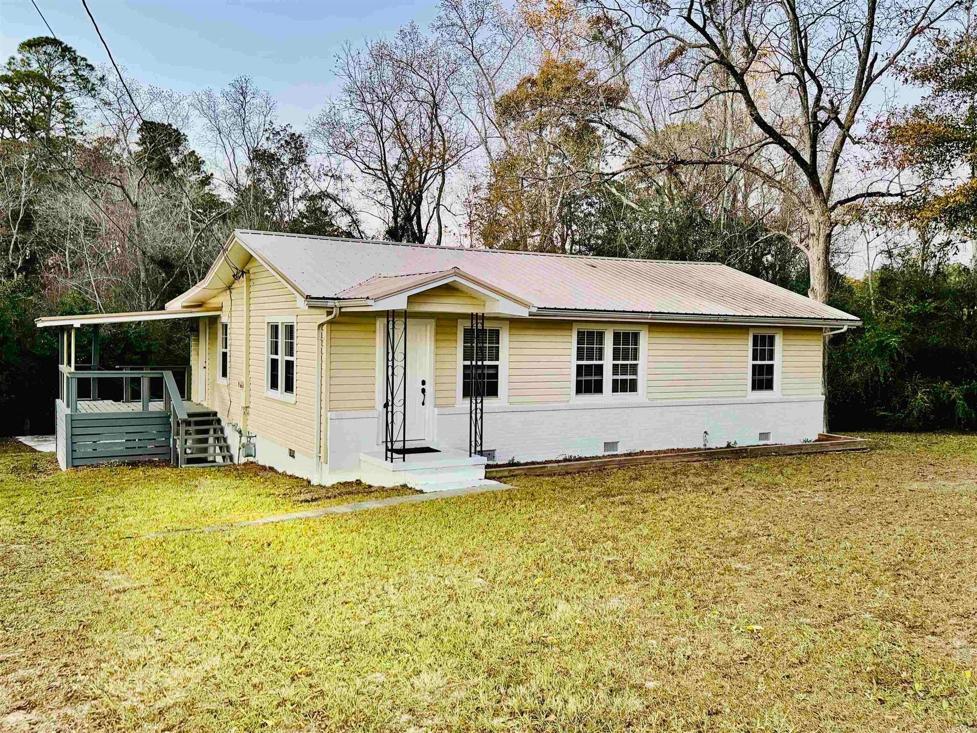 Yellow house with metal roof, porch, and open yard.