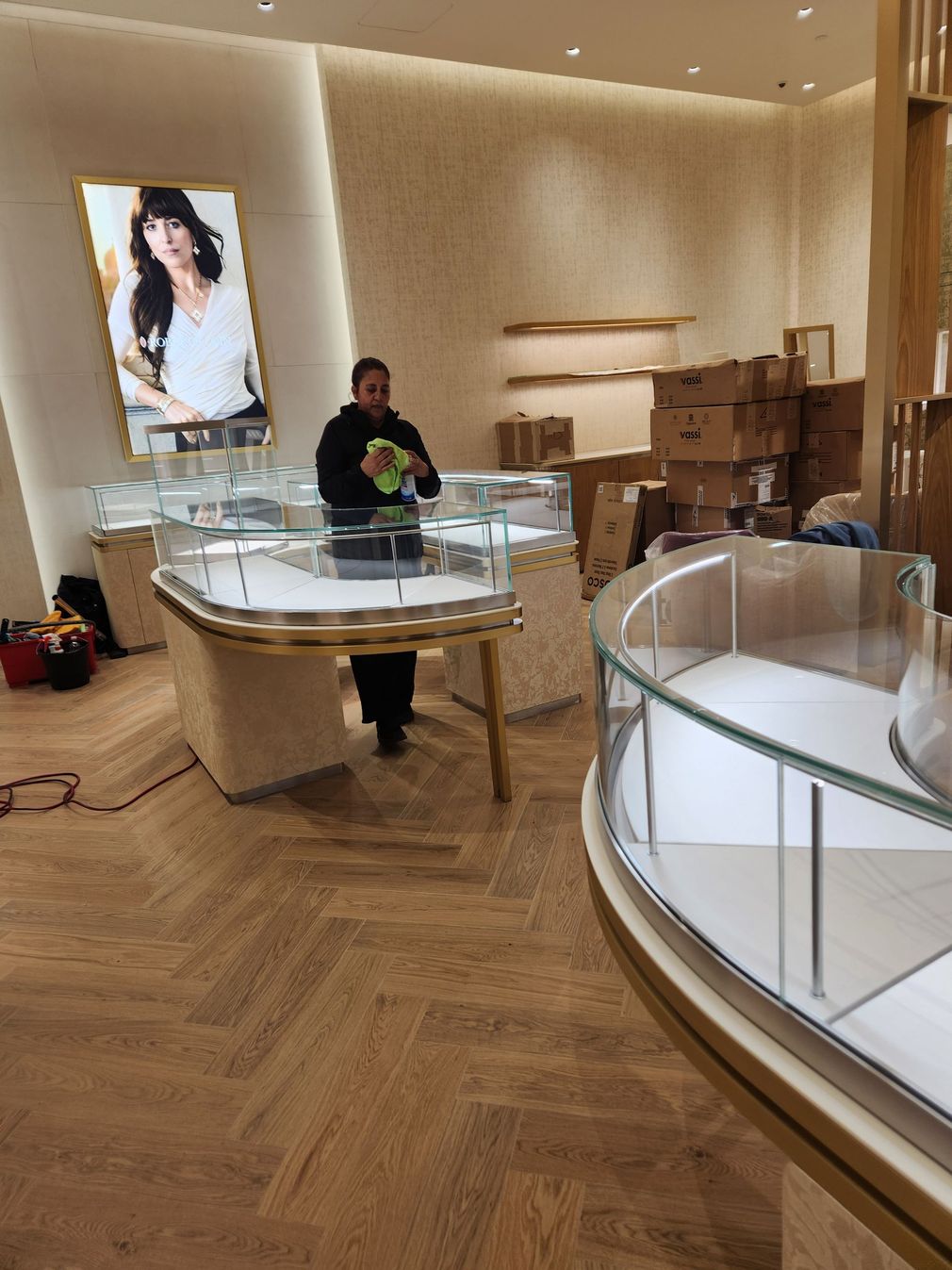 Boutique jewelry store with glass display cases, wood floors, and a person standing near the center.