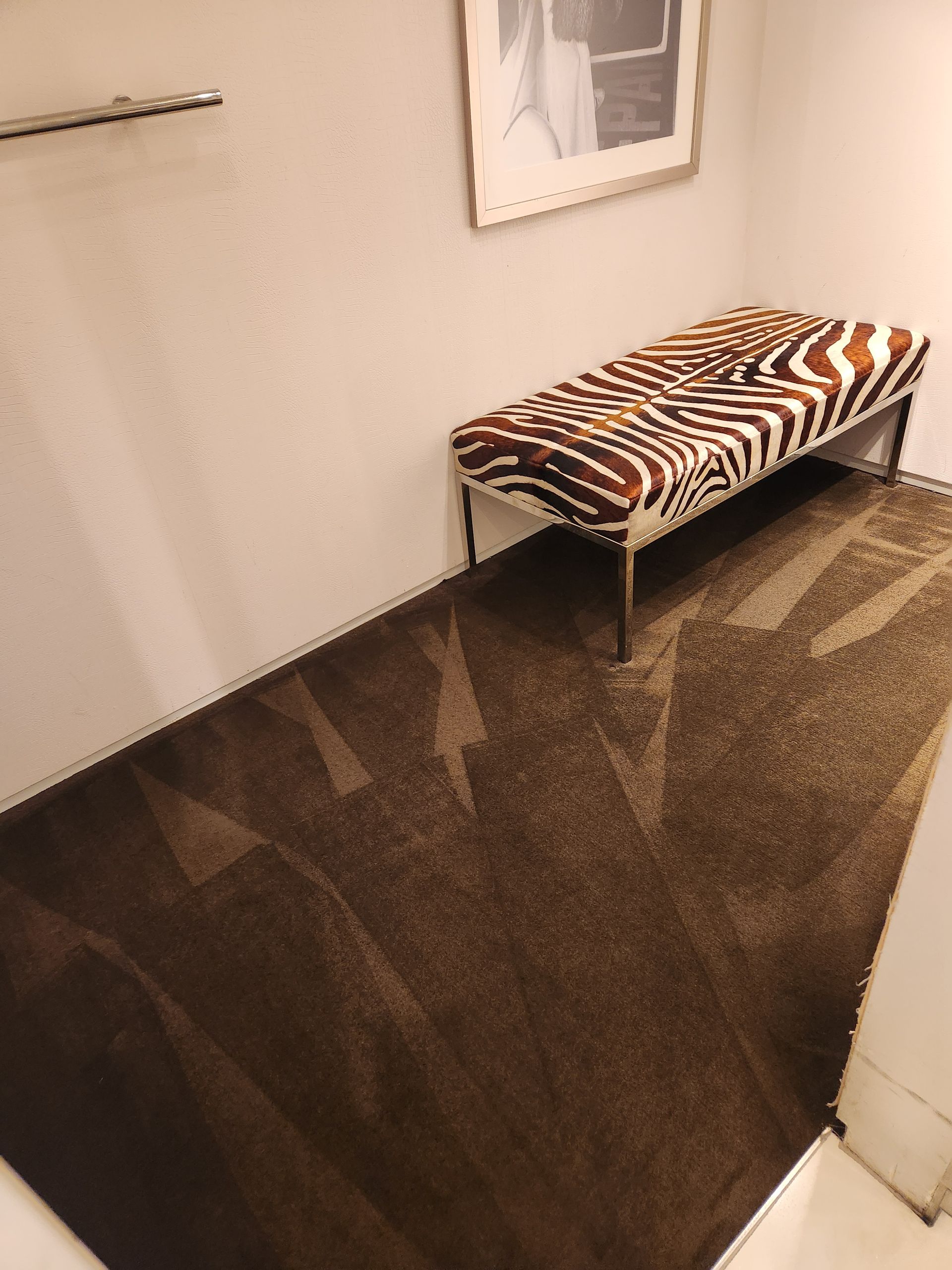 Hallway with a zebra-print bench and dark glossy floor tiles