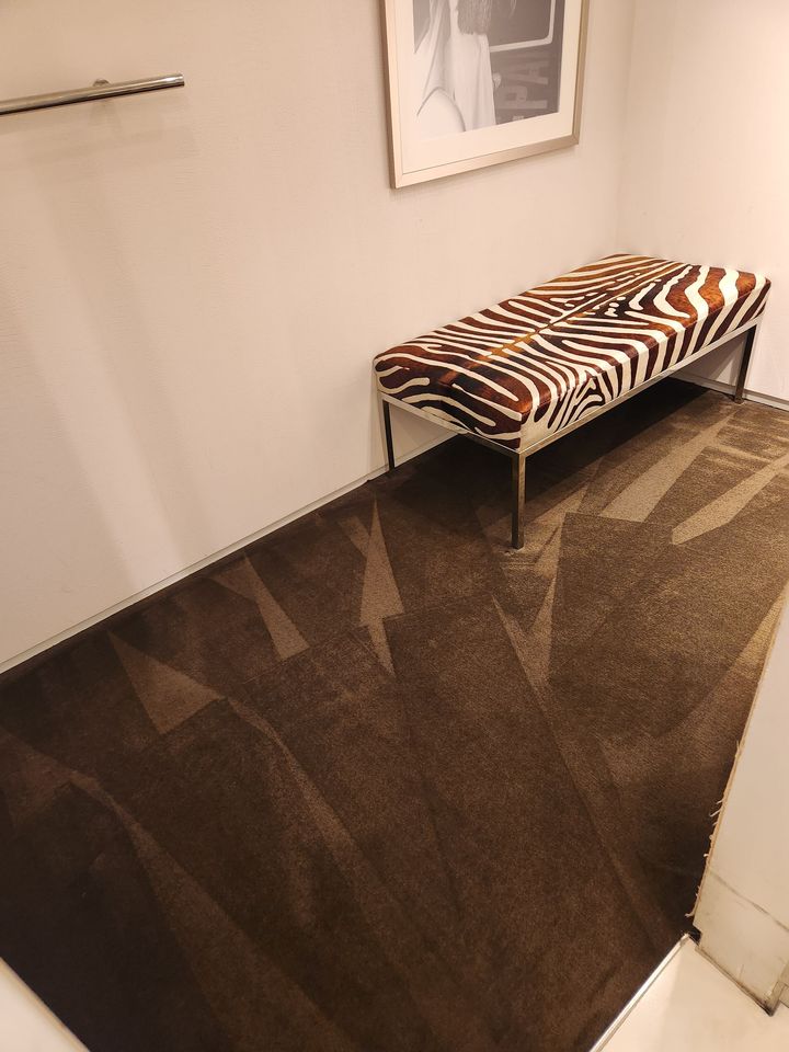 Hallway with a zebra-print bench and dark glossy floor tiles