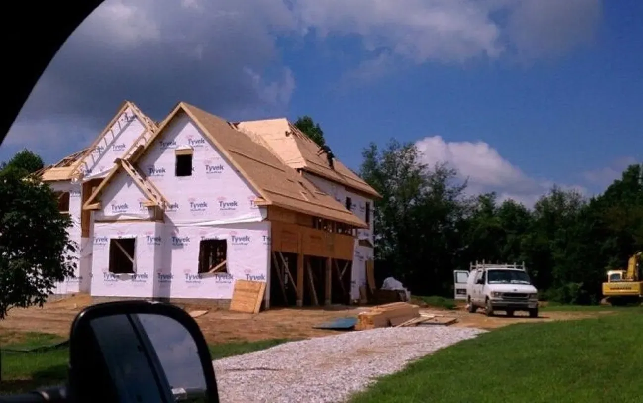 A white truck is parked in front of a house under construction