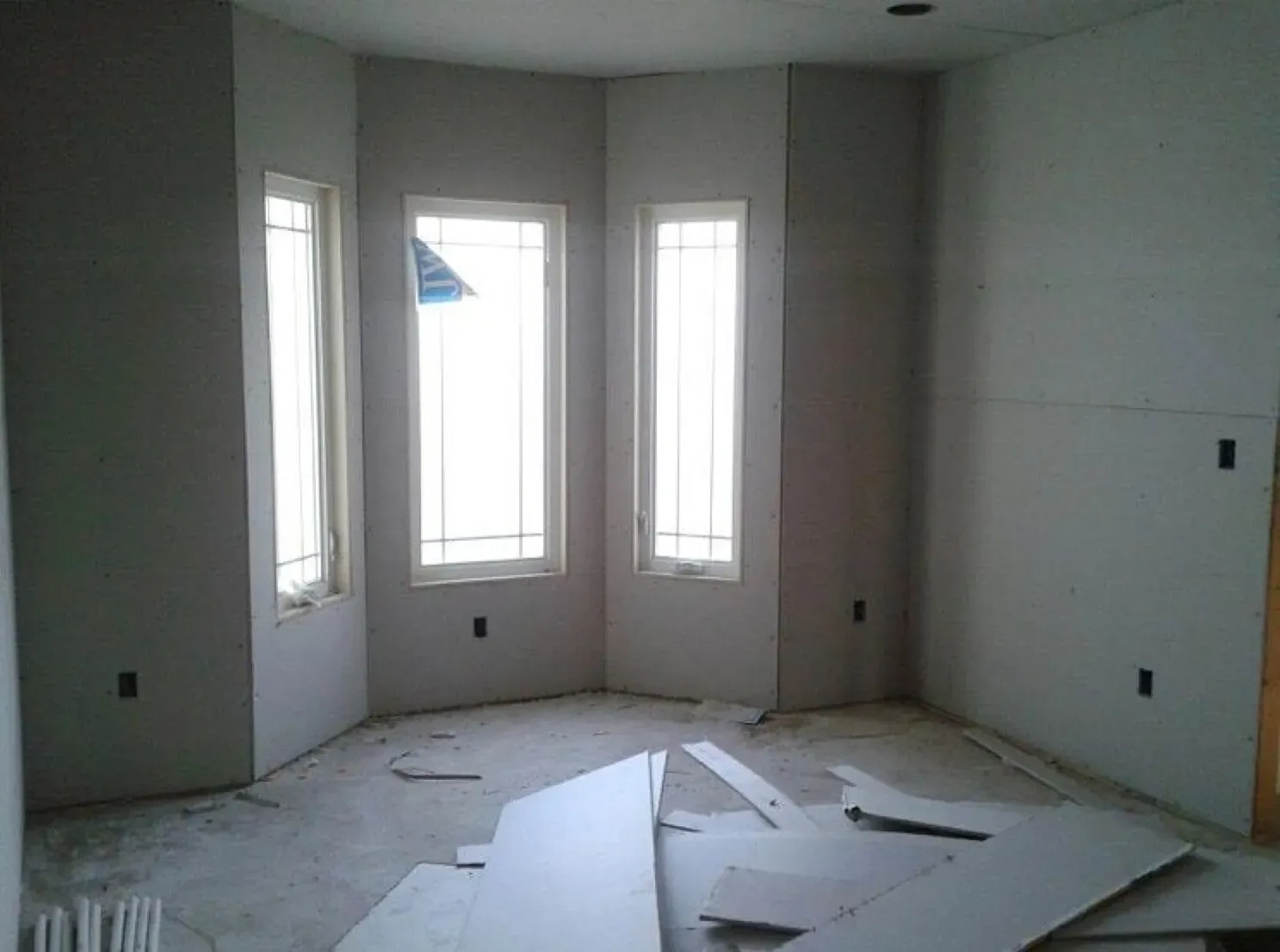 A room with a lot of windows and drywall on the floor.