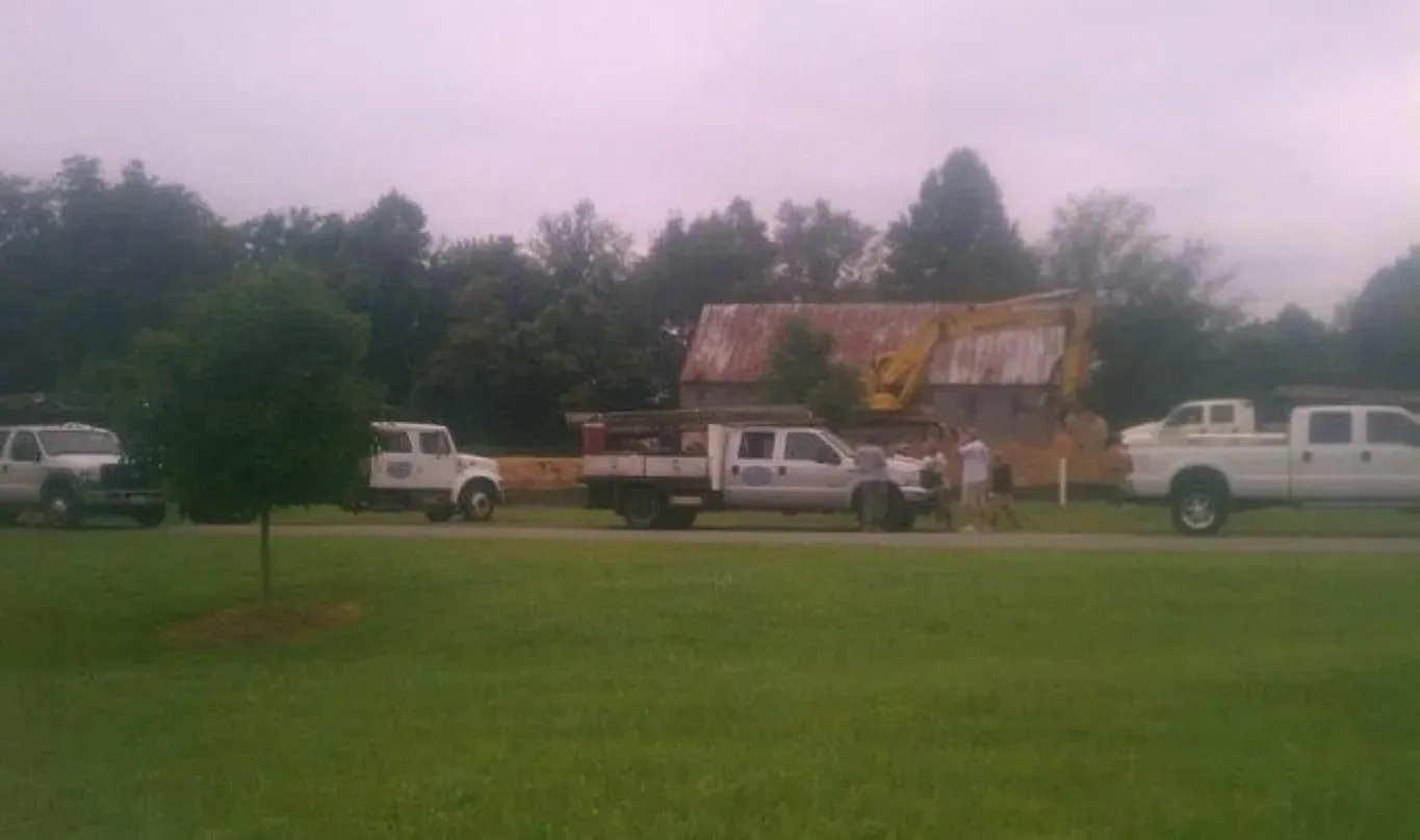 A row of trucks are parked in front of a house under construction.