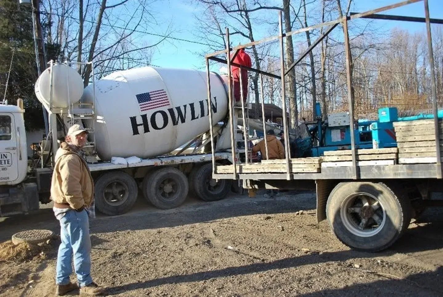 A man stands in front of a howlin concrete mixer truck