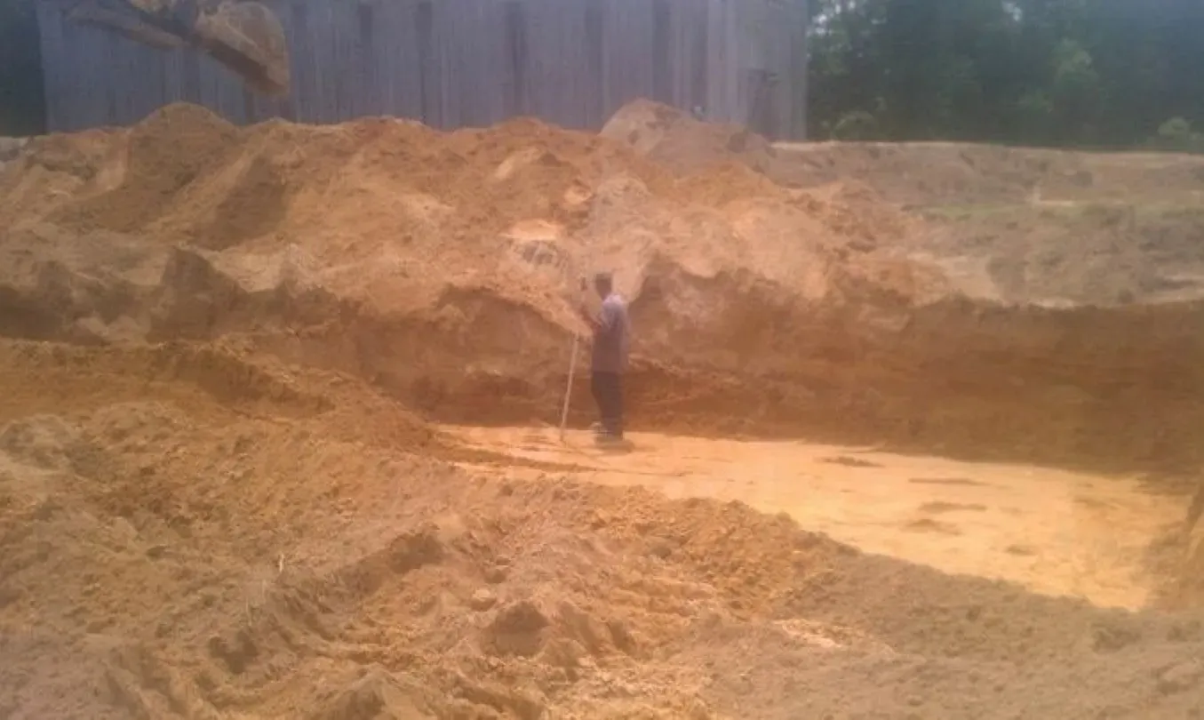 A man is standing in a large pile of dirt.