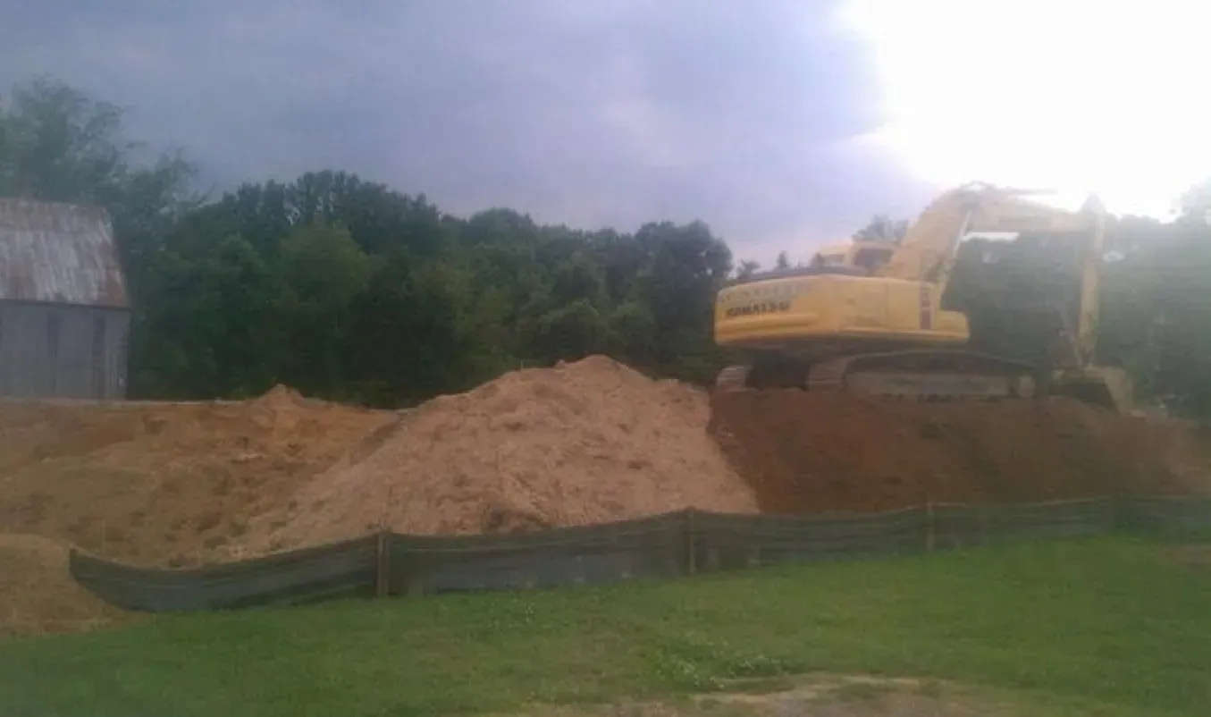 A large yellow excavator is sitting on top of a pile of dirt.