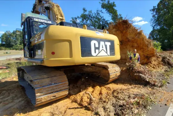 A cat excavator is digging a hole in the dirt.