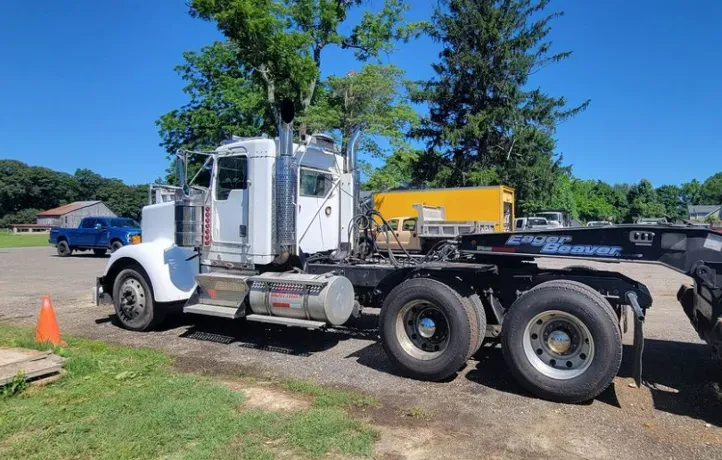 A semi truck with a trailer attached to it is parked in a parking lot.