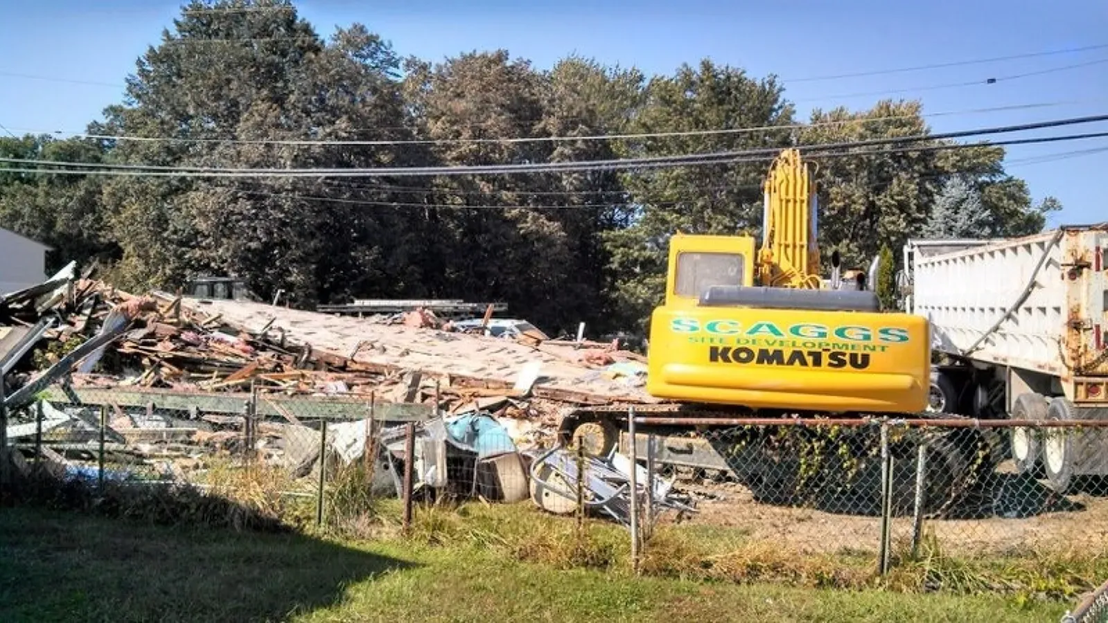 A yellow komatsu excavator is being used to demolish a building.