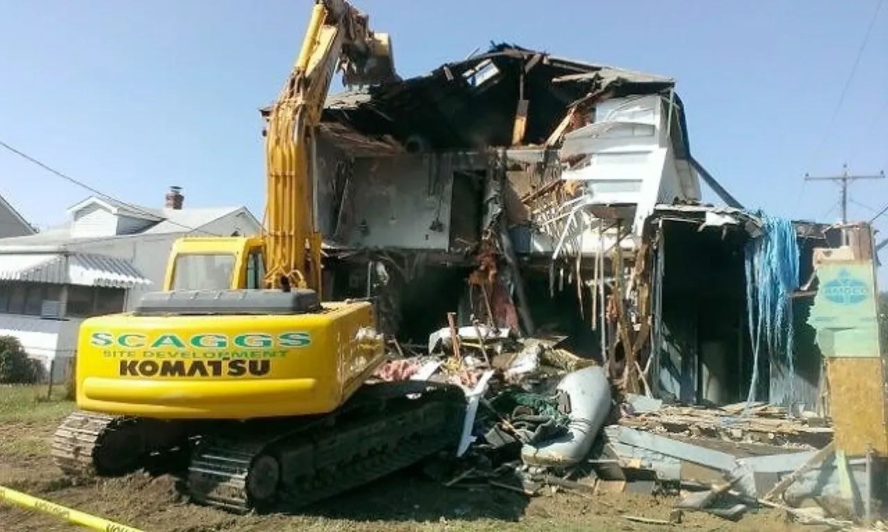 A komatsu excavator is demolishing a building.  