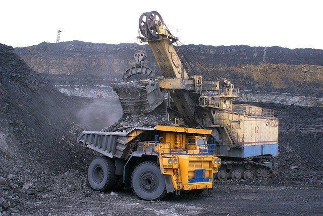 A yellow dump truck is being loaded with coal in a coal mine.