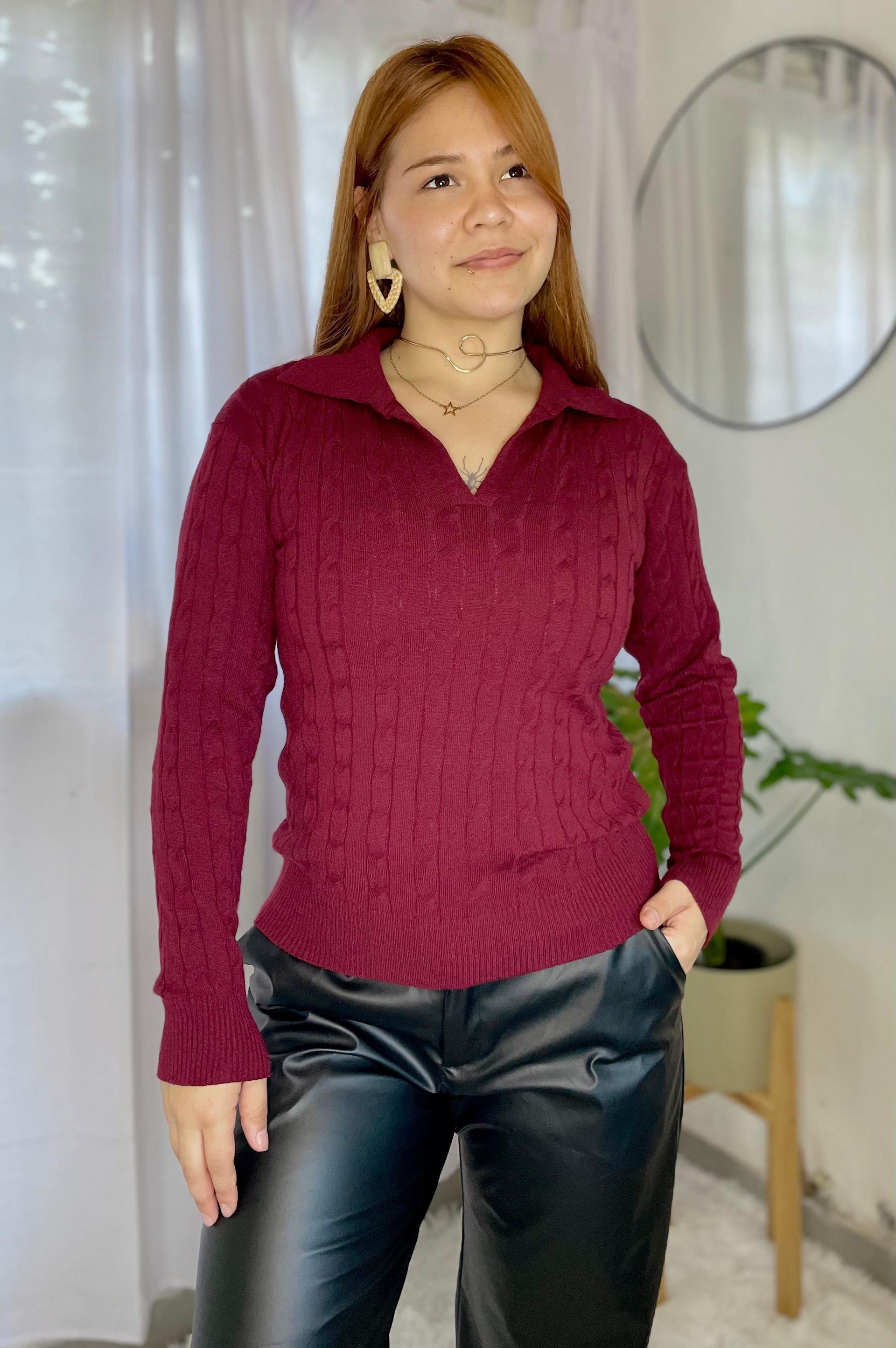 Mujer de pie en el interior de una vivienda, vestida con un jersey