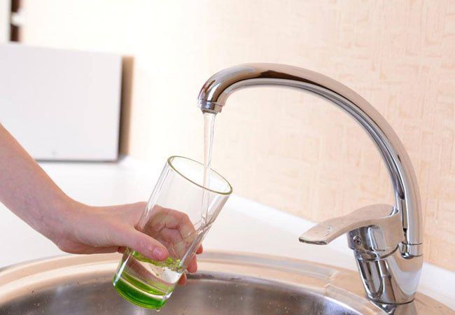 Water flowing into a glass from a sink tap