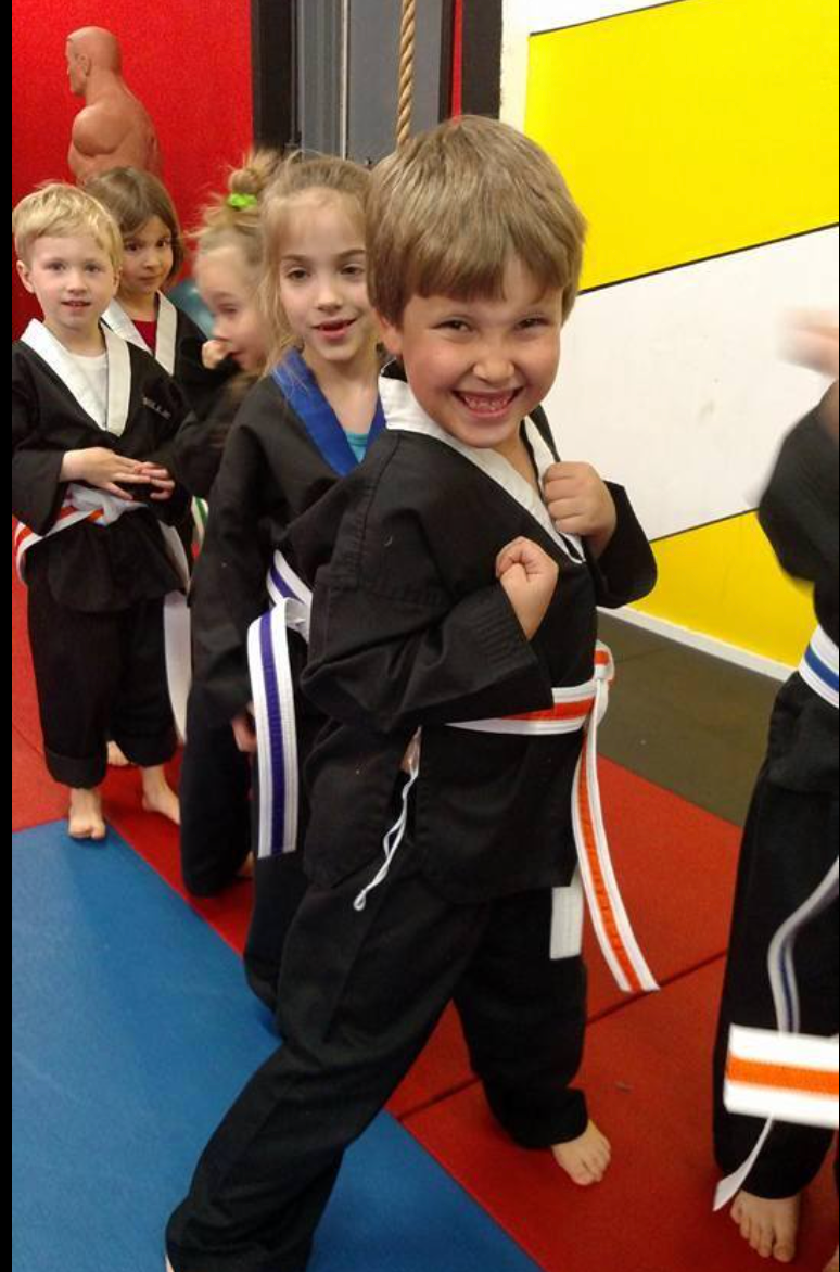 A group of young children are wearing black karate uniforms