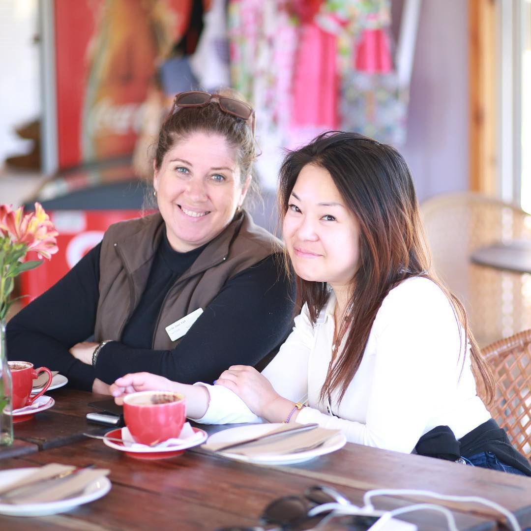 Two women smile at a table in a cafe