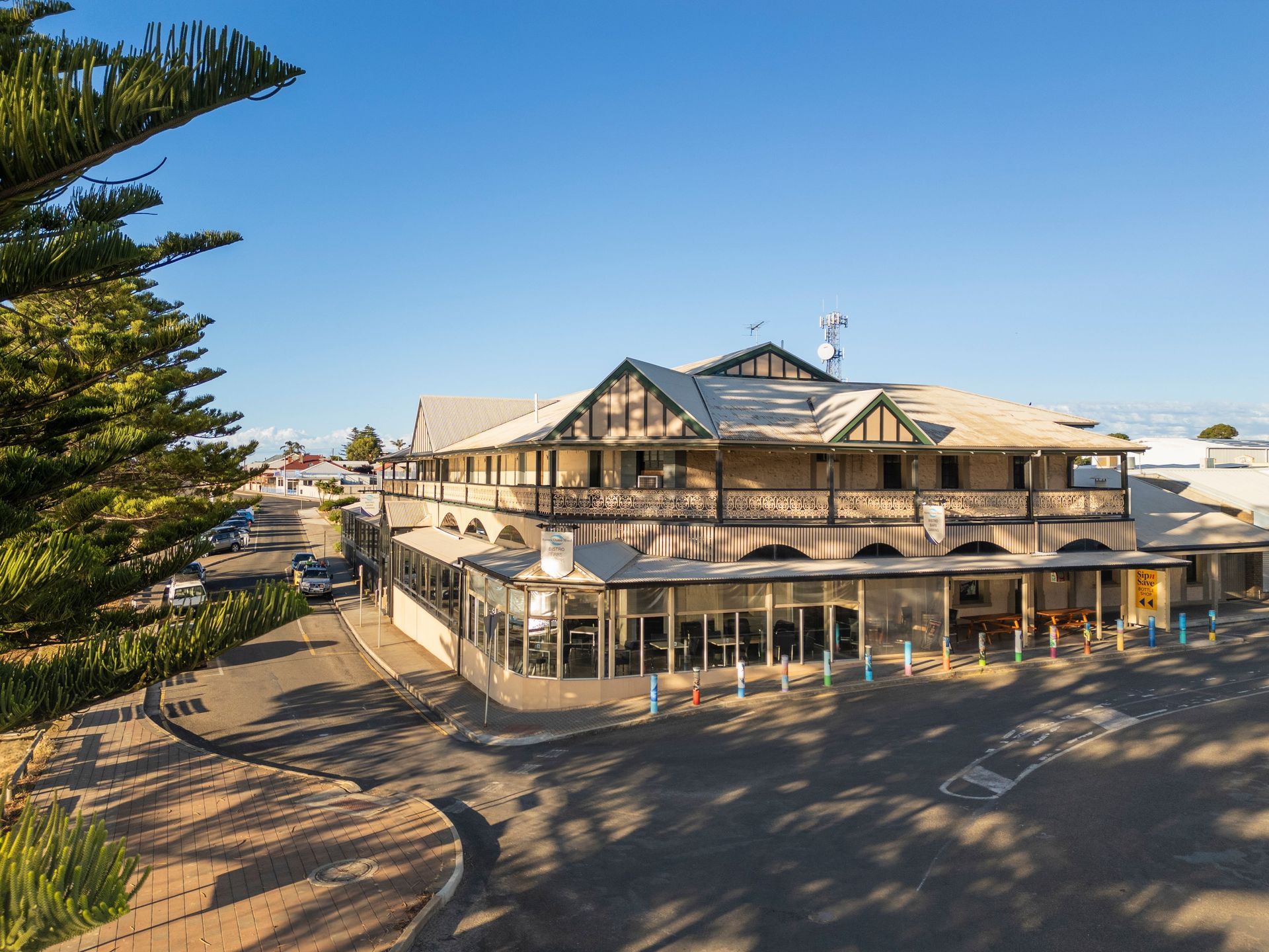 Exterior of a beige seaside building with a wraparound veranda under a clear blue sky