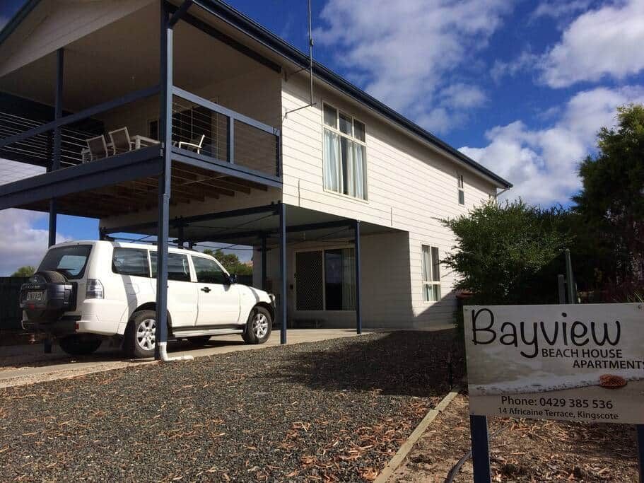 Bayview building exterior with parked white SUV and sign under a blue sky