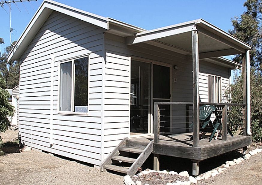 Small white house with porch and steps in a dry yard