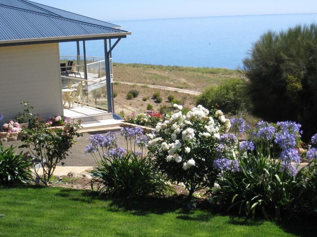 Garden with blooming flowers beside a seaside house overlooking calm blue water