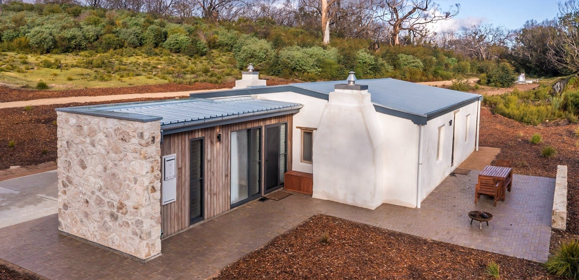 Modern tiny house with white and stone exterior in a landscaped yard