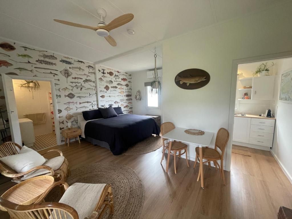 Bright bedroom with black bed, wicker chair, round table, and patterned wallpaper, viewed from the doorway