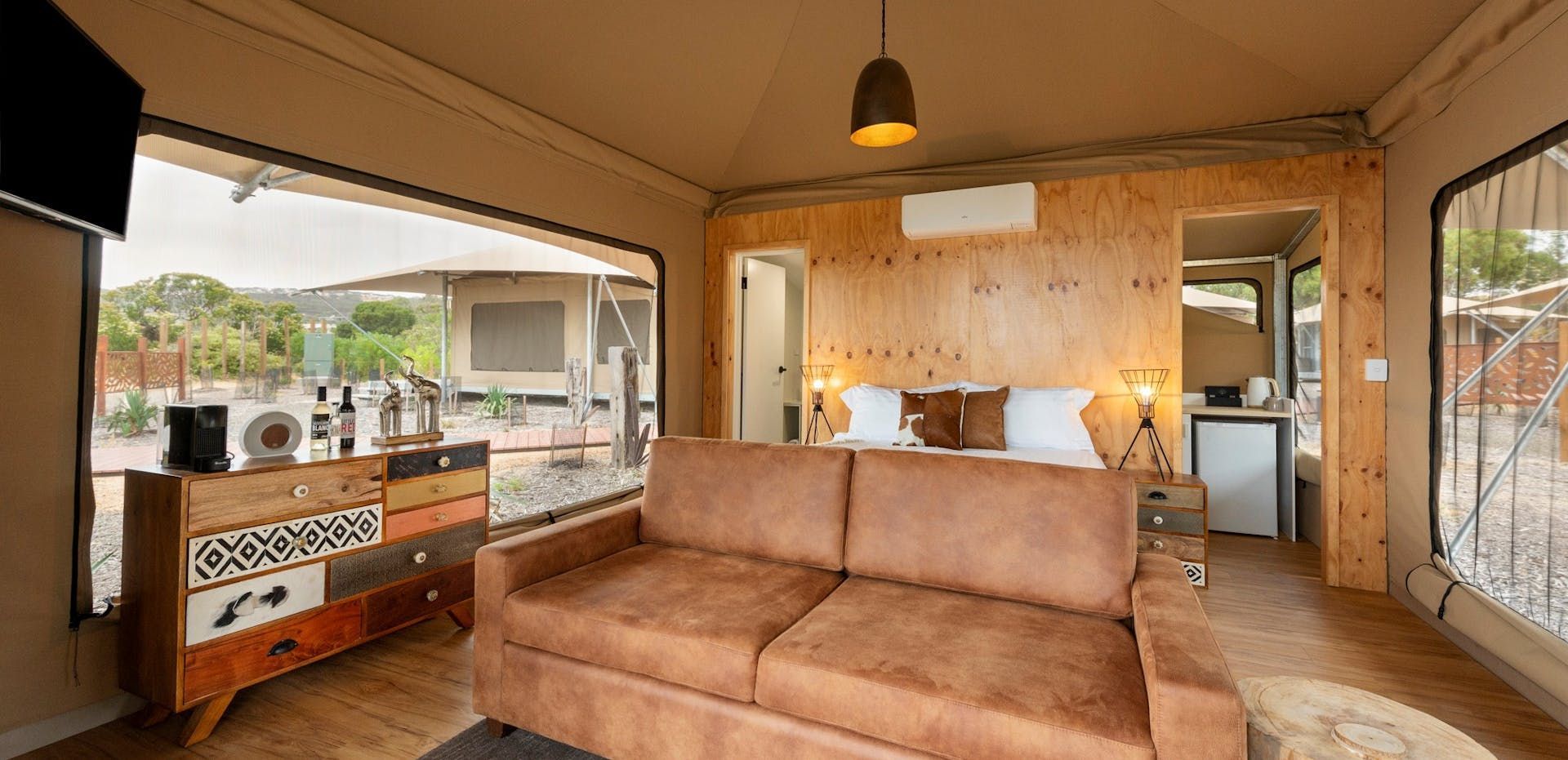 Covered patio with tan sofa, wood-paneled wall, sideboard, and sliding glass doors opening to a yard
