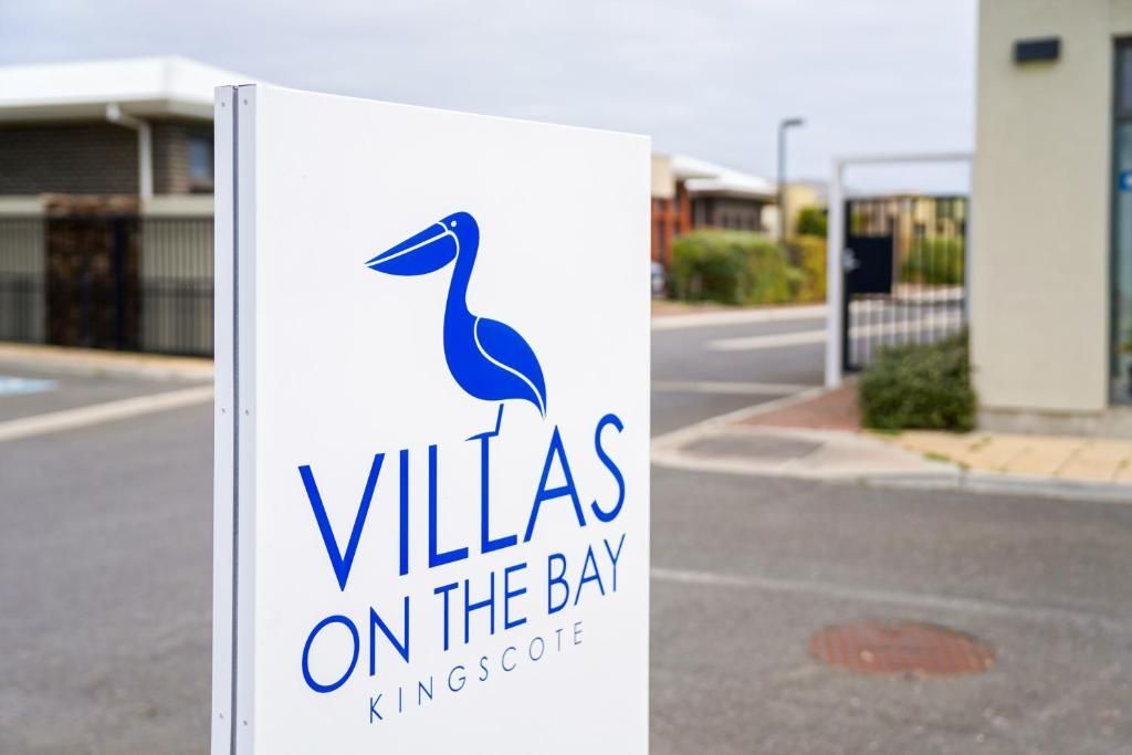 Sign for Villas on the Bay, a blue bird logo on a white post outside a residential area