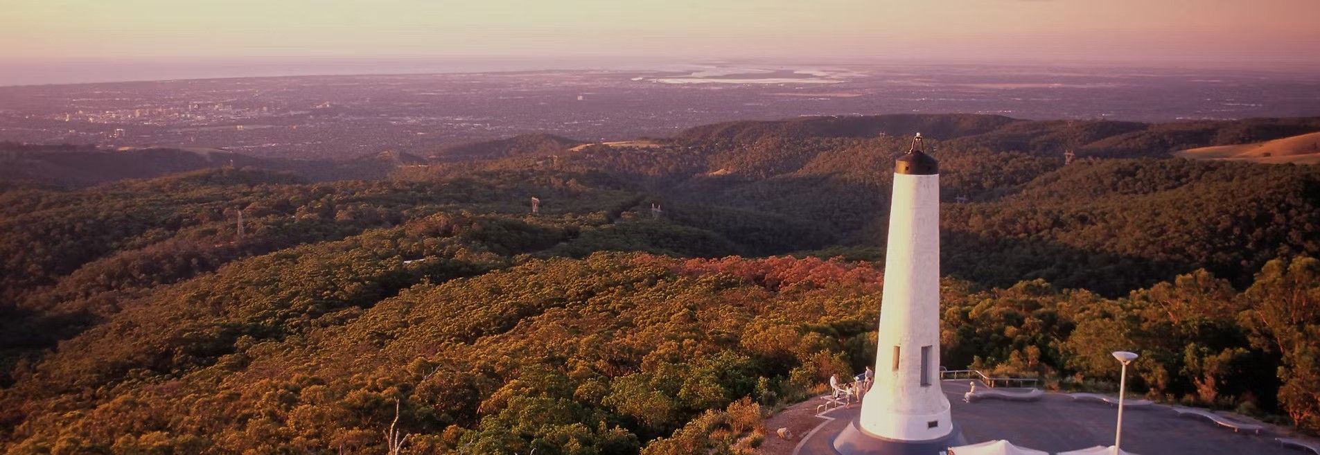 A white tower on a mountaintop overlooking a forested landscape
