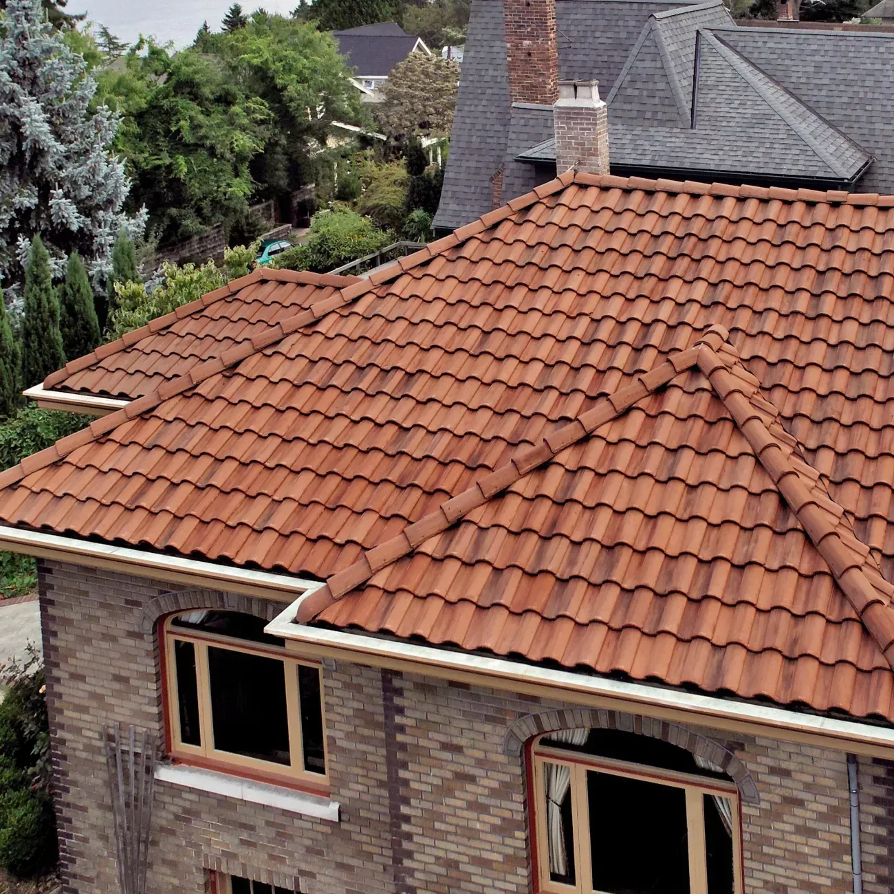 An aerial view of a residential roof undergoing construction, featuring grey shingles and bright green underlayment.