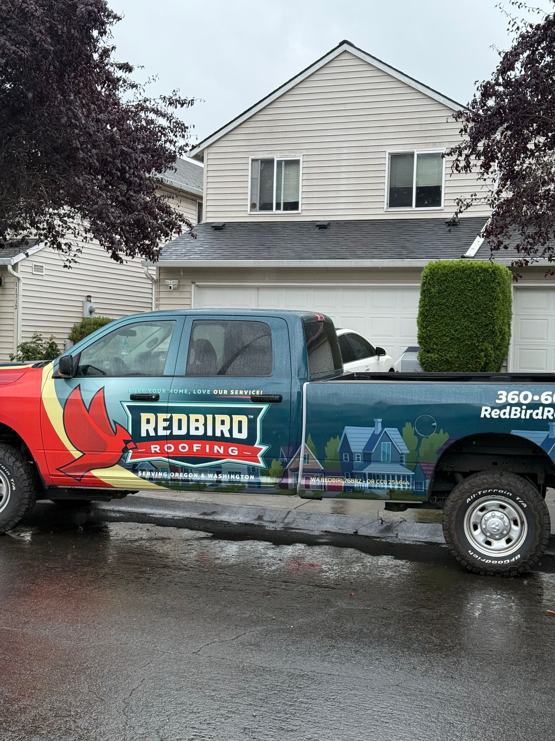 A Redbird Group pickup truck parked on a residential street in front of a house.