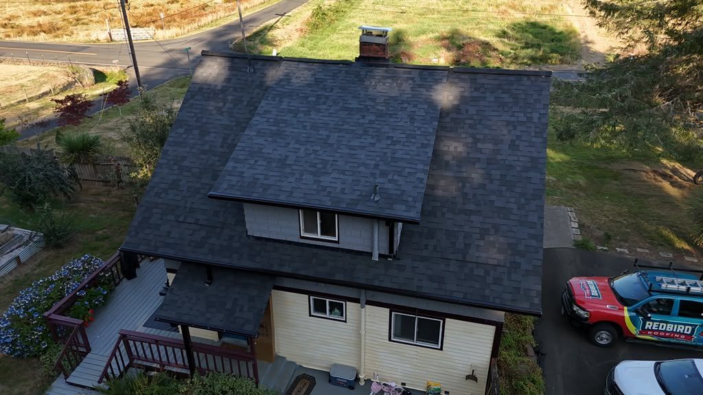 Aerial of the finished dark Malarkey shingle roof with a RedBird truck parked in the driveway