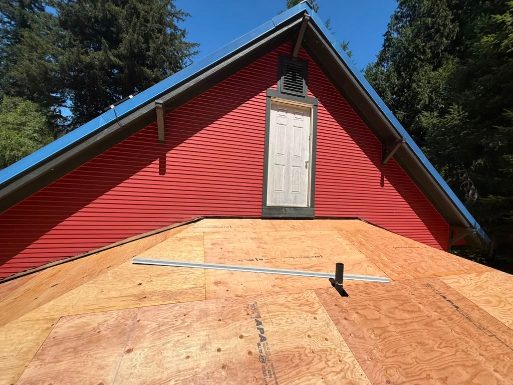 Red house gable with boarded window and plywood roof under construction