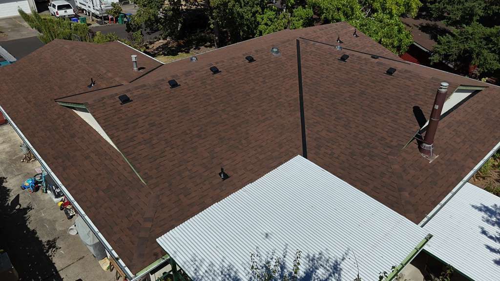 Aerial of the completed brown shingle roof showing sealed valleys and a new pipe flashing