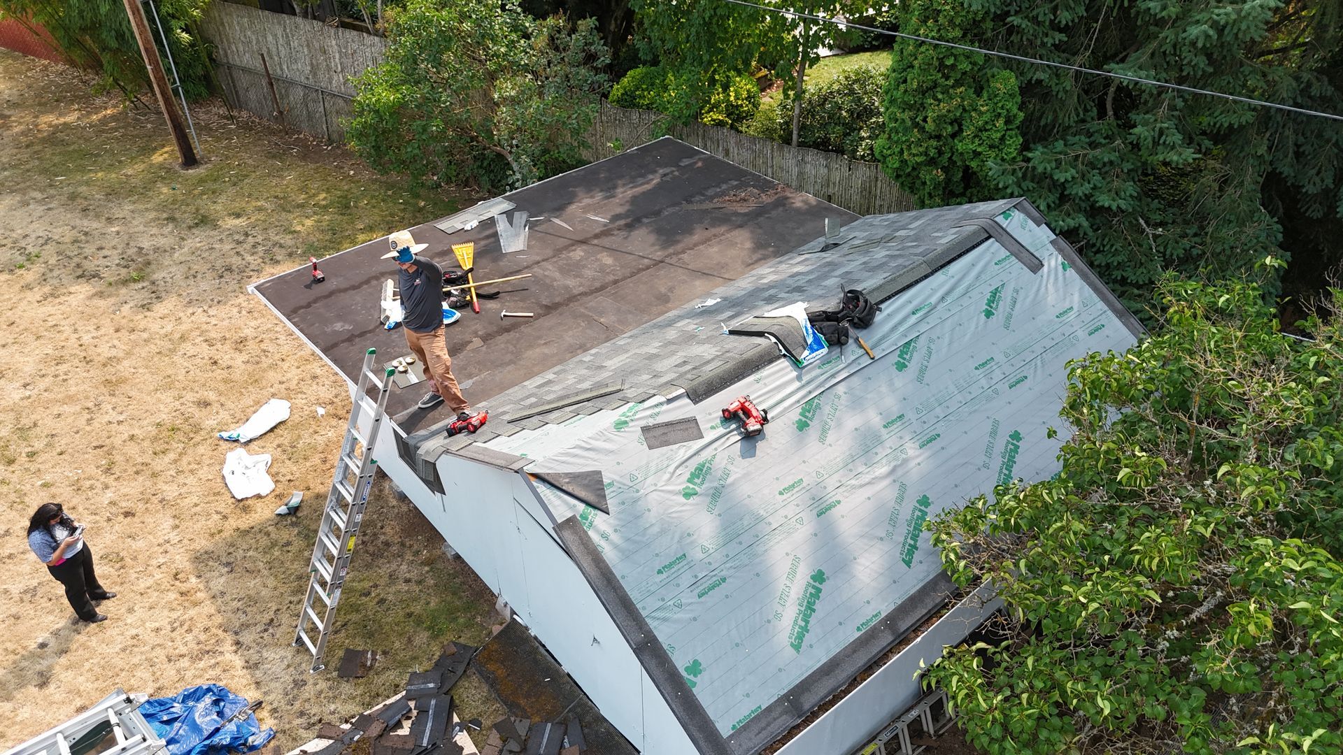 A high-angle view of construction workers installing new roofing materials on a home’s sloped roof.