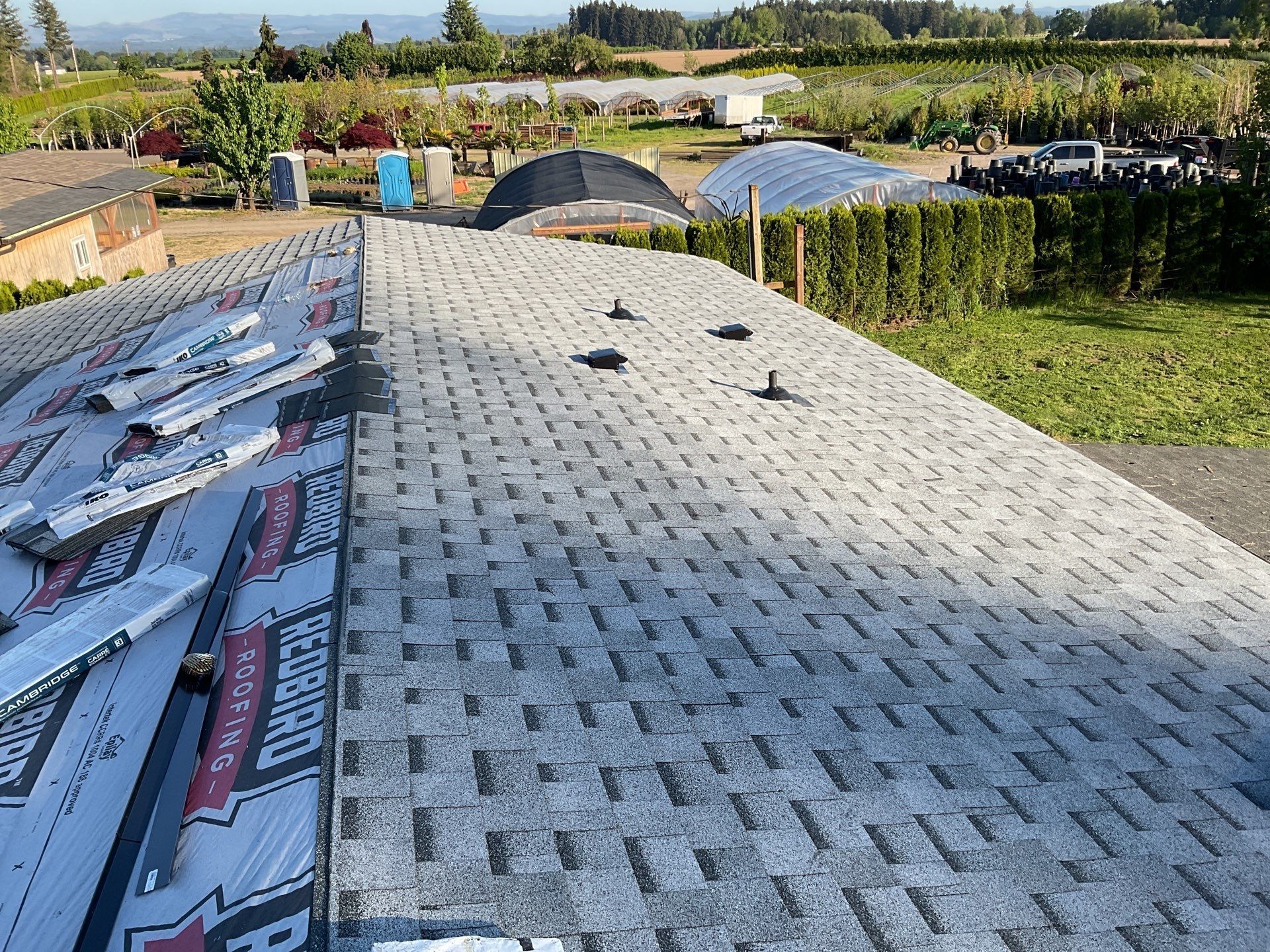Gray architectural shingles being installed on a Canby, OR roof, bundles staged on the slope