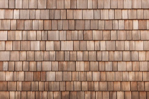 A uniform, repeating pattern of weathered, light brown wooden shingles or tiles arranged in overlapping horizontal rows.