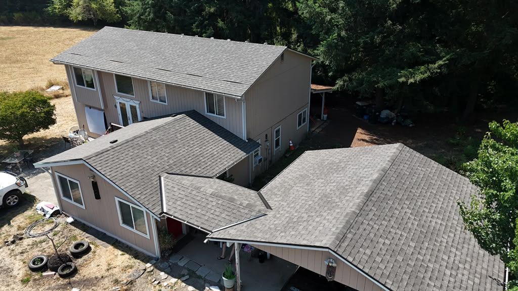 Aerial of the finished shingle roof on a two-story Olympia home surrounded by evergreen trees