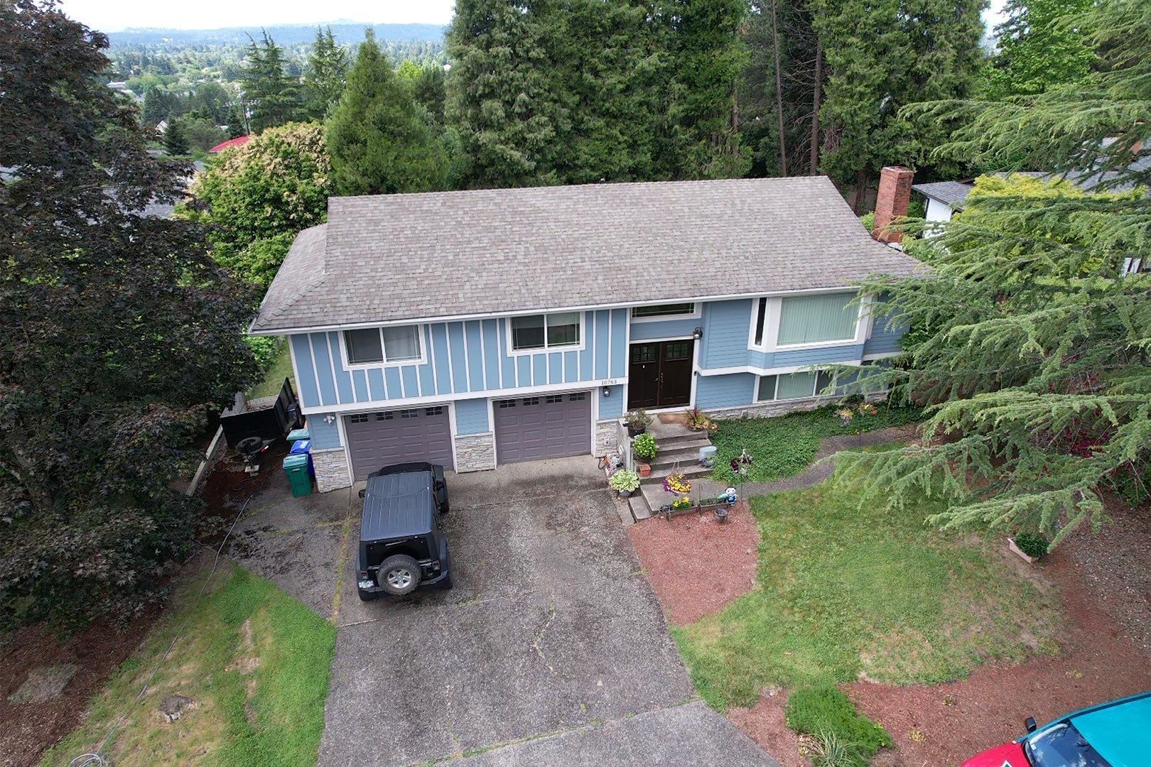 Worn gray shingle roof on a blue split-level home before its replacement