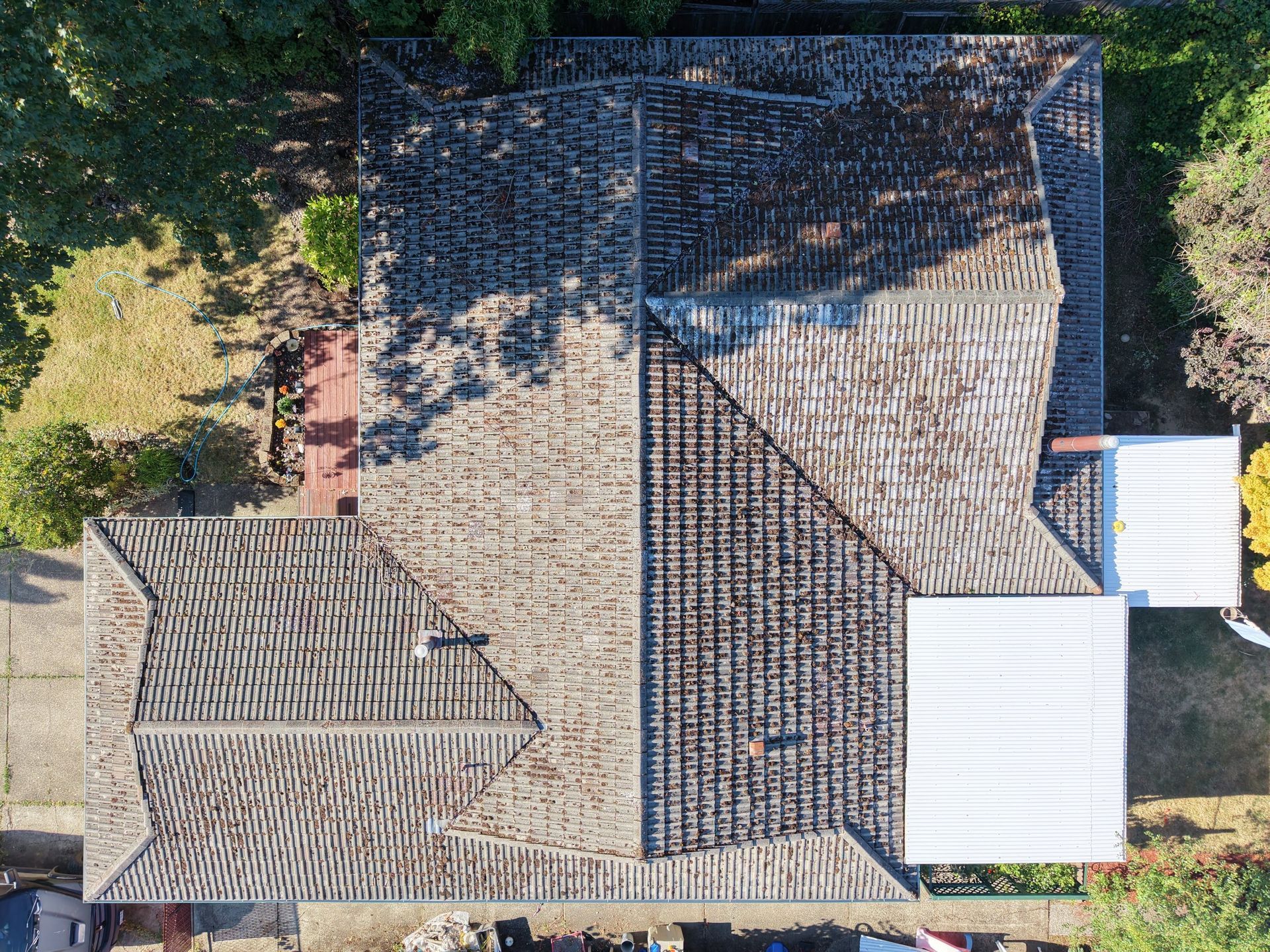 Overhead aerial of a full concrete tile roof showing moss buildup and worn tiles across every slope