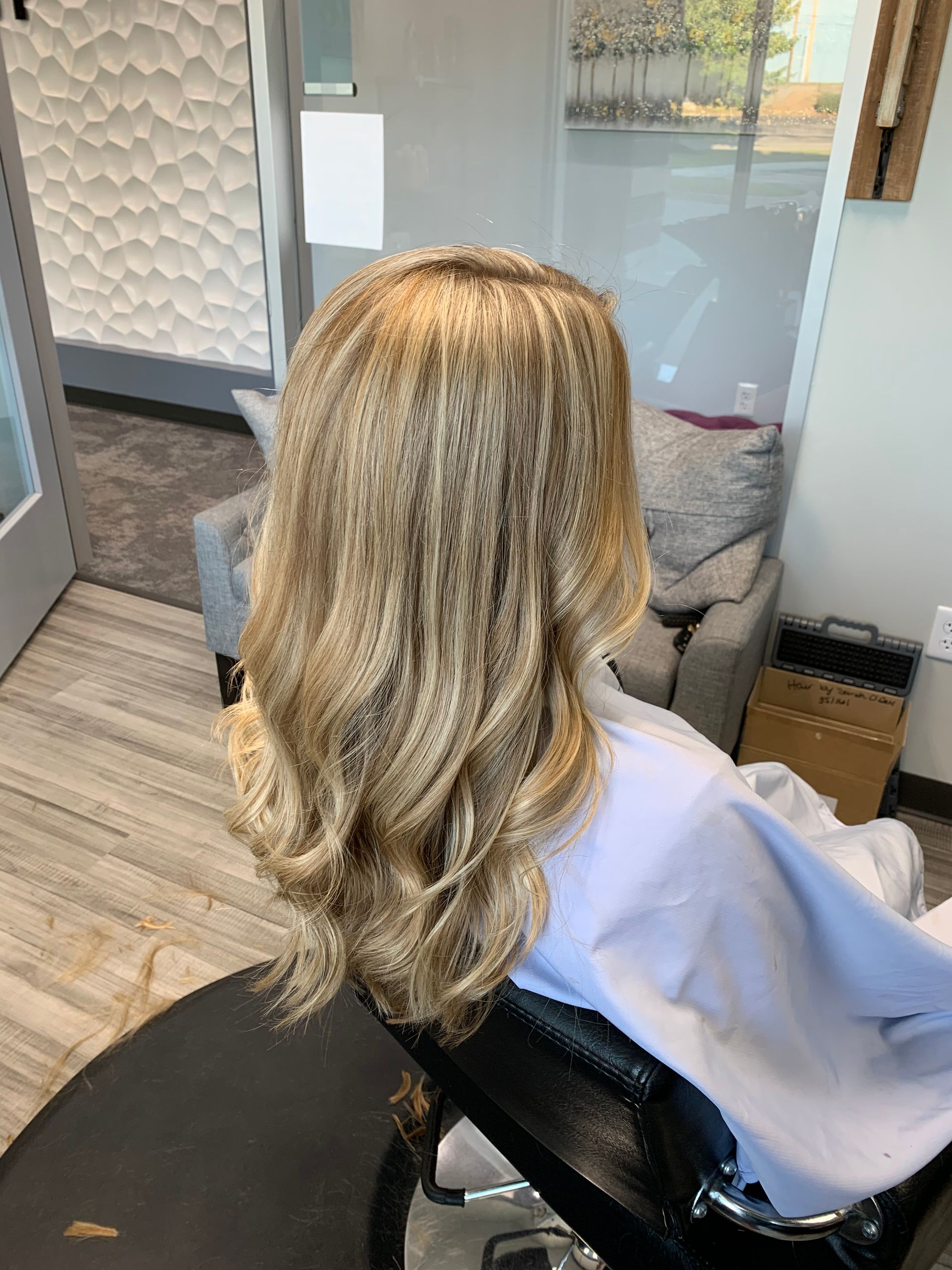 A woman is sitting in a chair with her hair in a salon.