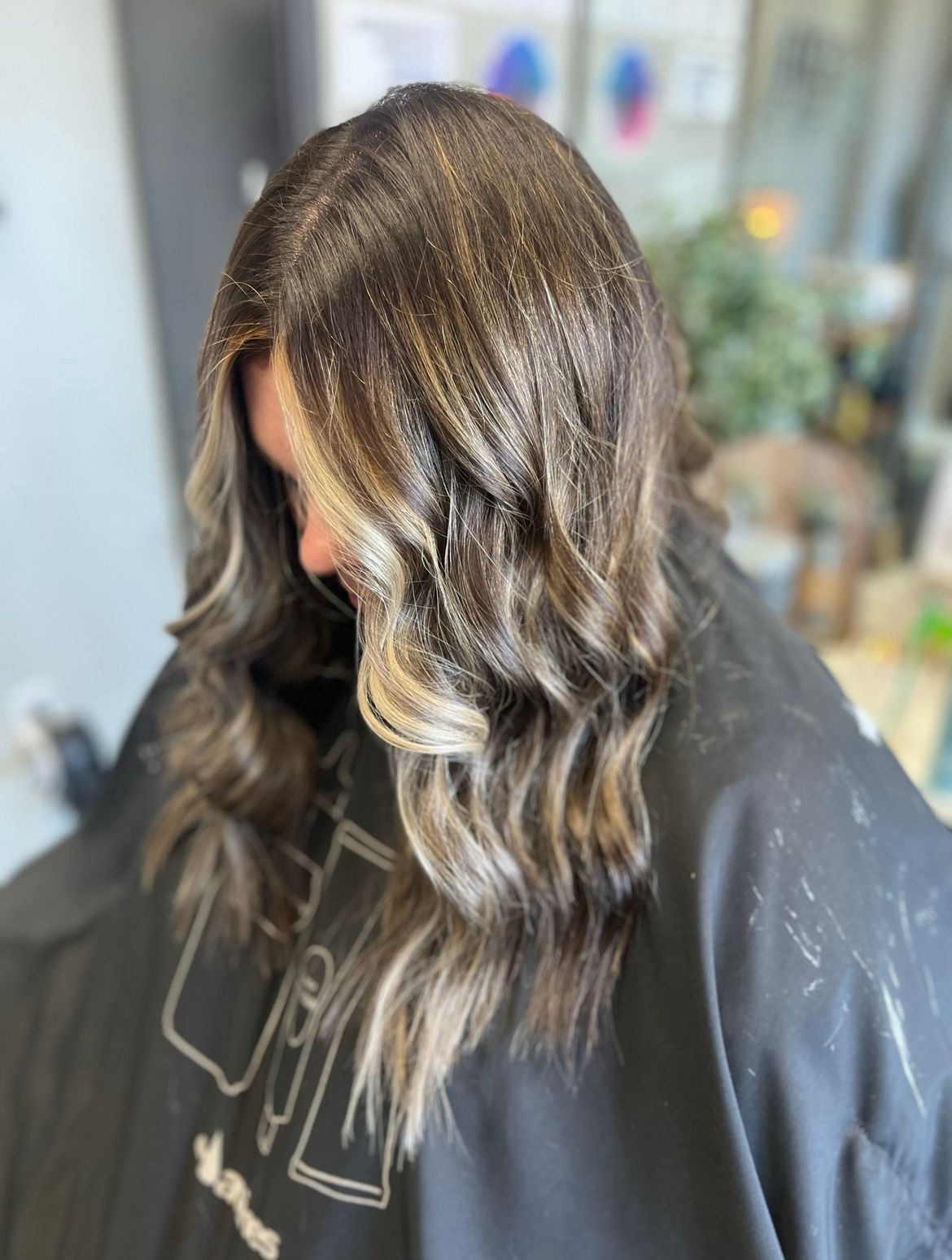 A woman with long brown hair is sitting in a chair in a salon.
