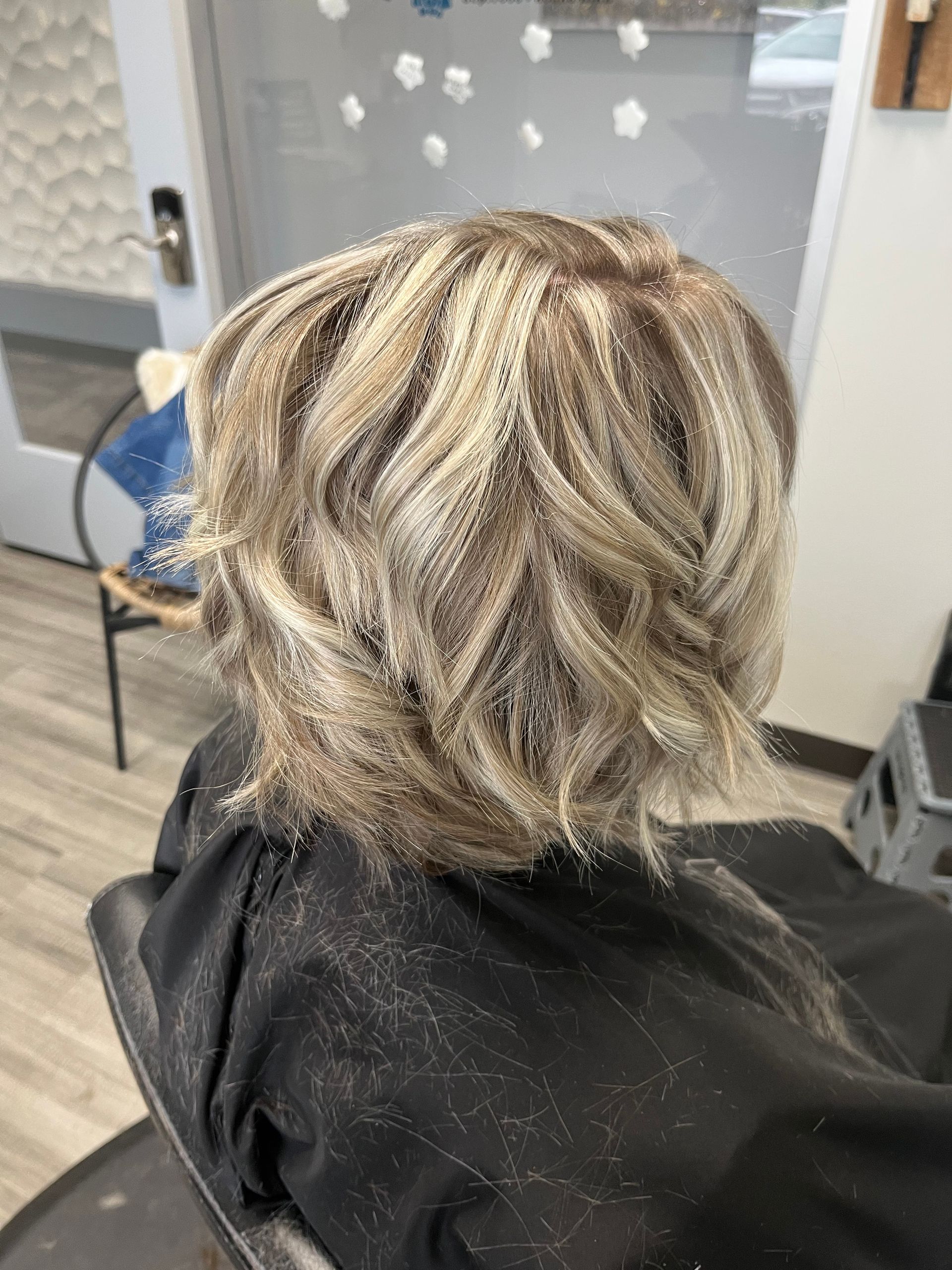 A woman is sitting in a chair with her hair in a bun.