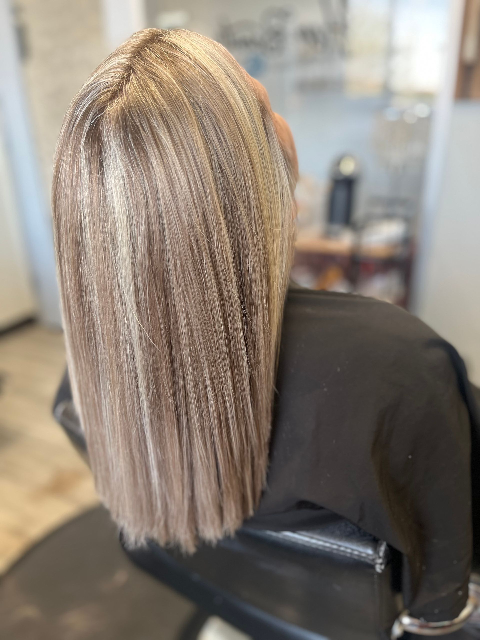 A woman with blonde hair is sitting in a chair in a salon.