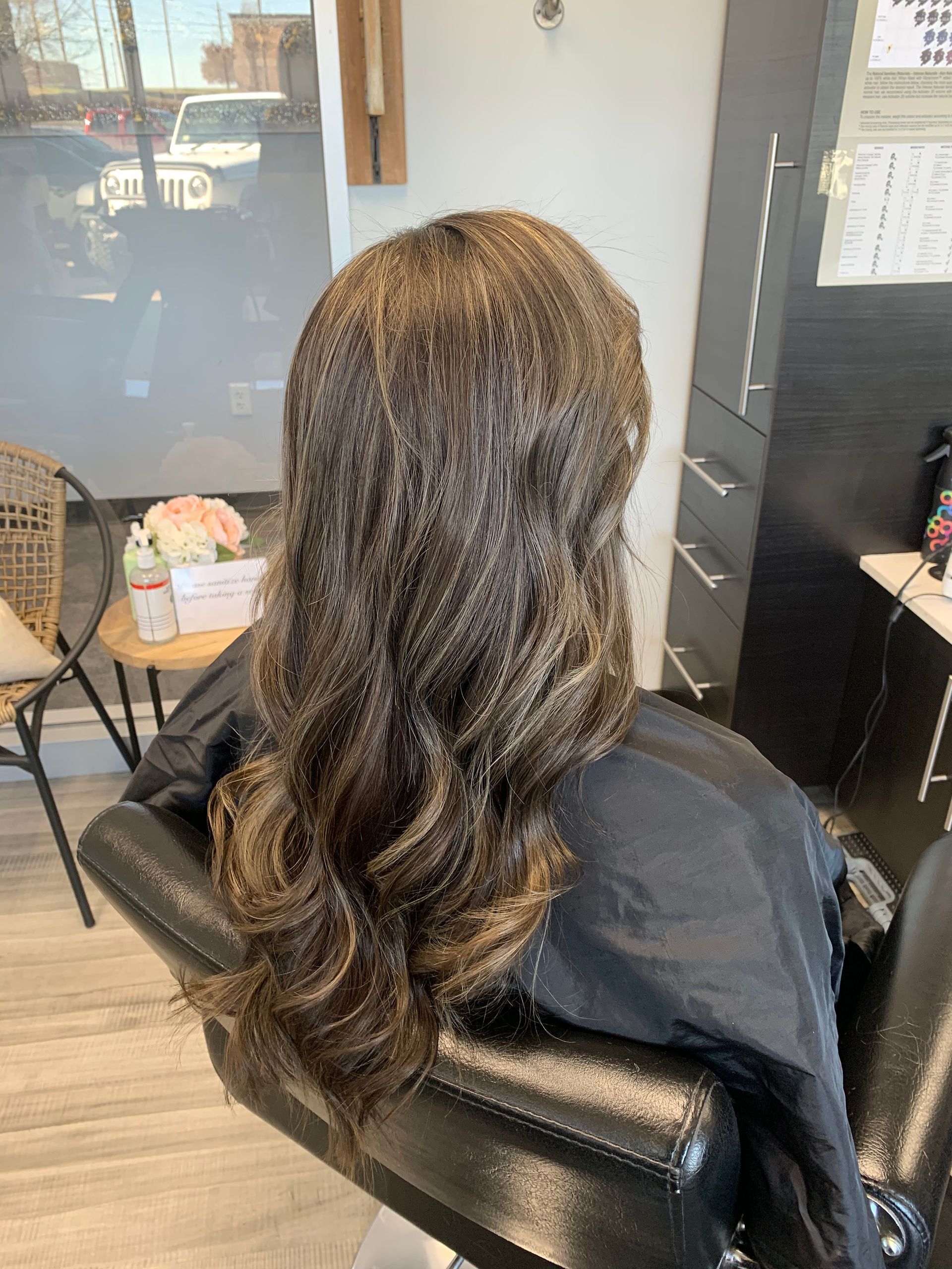 A woman is sitting in a chair with her hair in a salon.