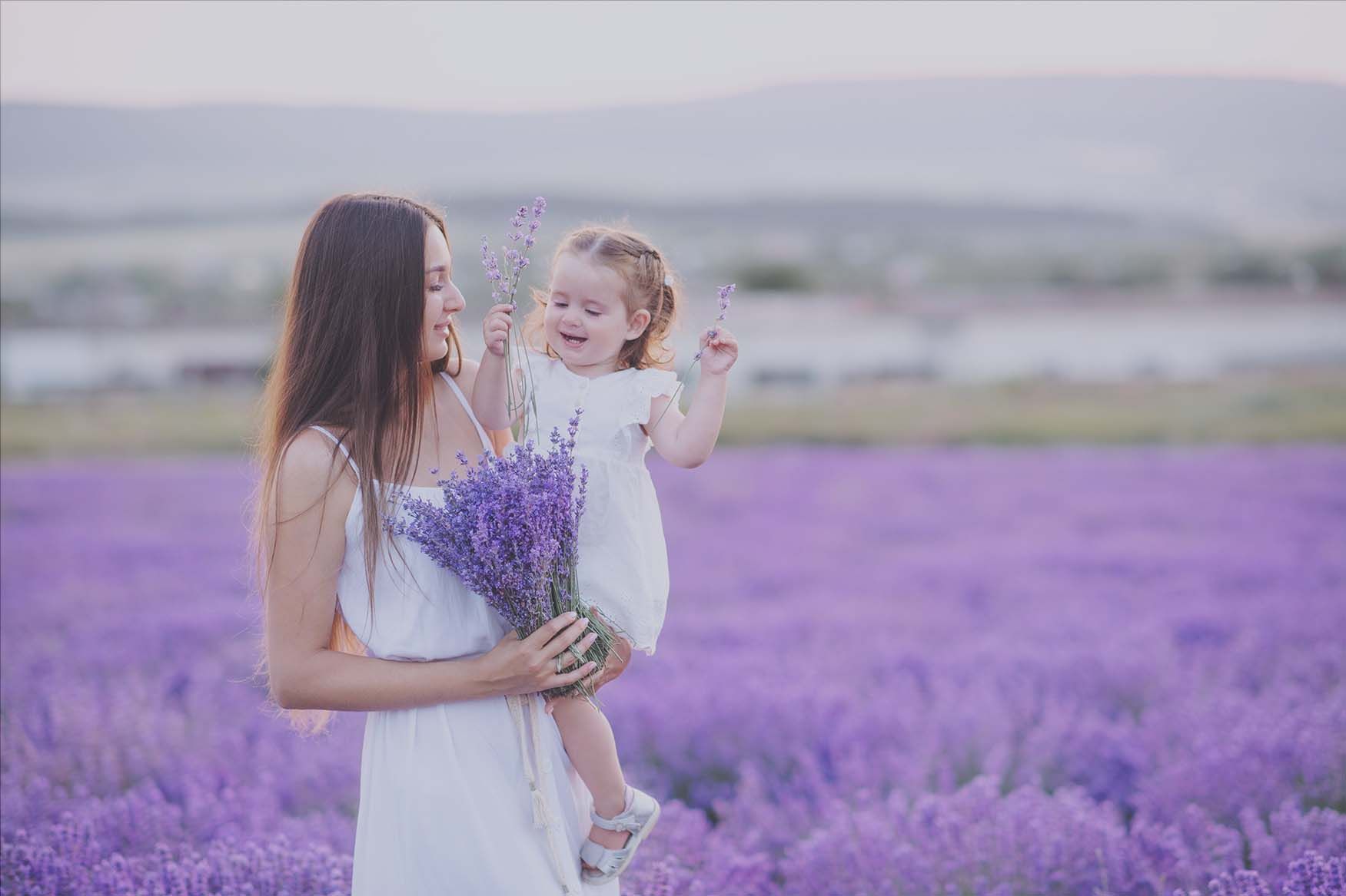 A woman is holding a little girl in a lavender field.
