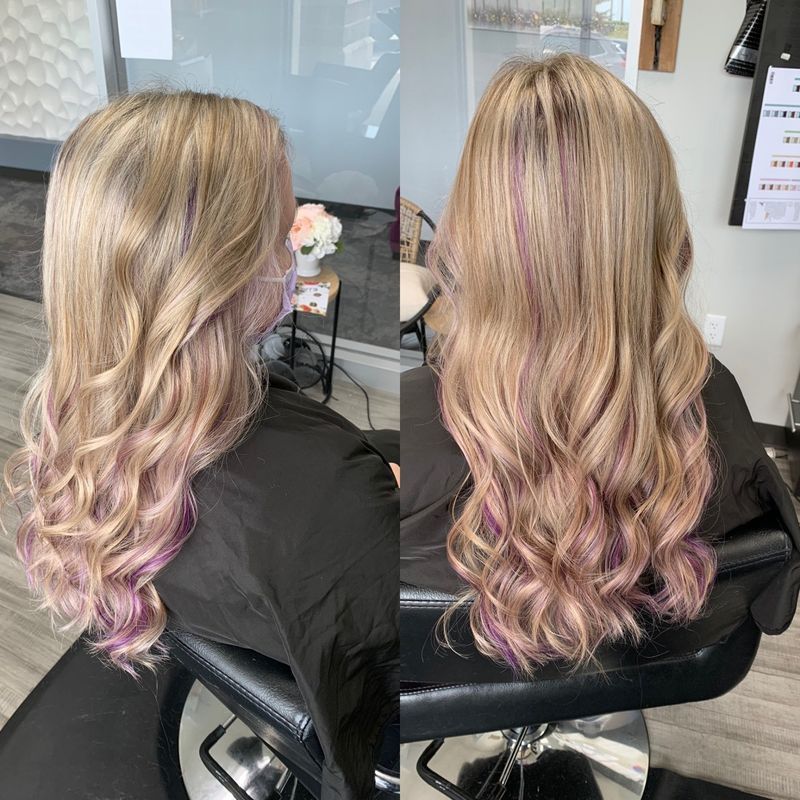 A woman with blonde and pink hair is sitting in a chair.
