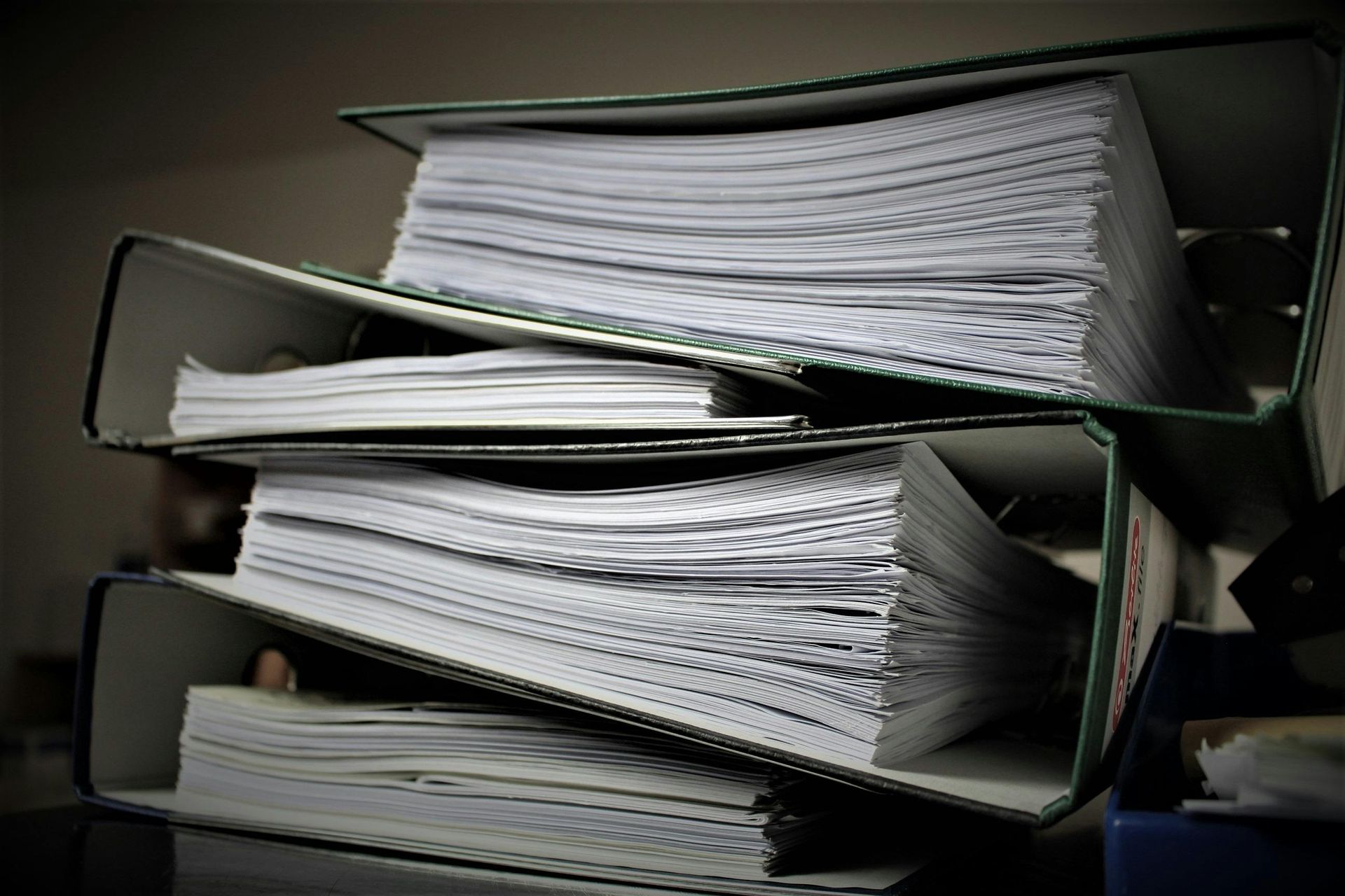 Three open file folders stacked with overflowing papers.